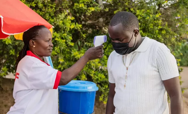 A health worker uses a thermometer to screen a man by the roadside in Bunia, Congo, Tuesday, May 19, 2026. (AP Photo/Moses Sawasawa)