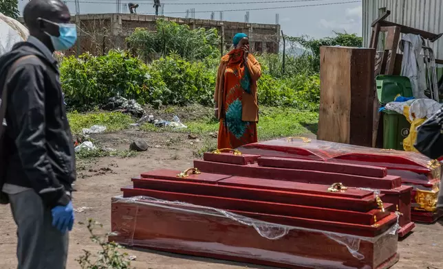 Family members of people who died of Ebola stand next to coffins at a health center in Rwampara, Congo, Wednesday, May 20, 2026. (AP Photo/Moses Sawasawa)
