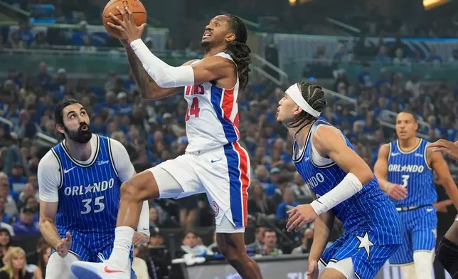 Detroit Pistons guard Daniss Jenkins (24) goes between Orlando Magic center Goga Bitadze (35) and guard Anthony Black for a shot during the first half in Game 4 of a first-round NBA basketball playoff series, Monday, April 27, 2026, in Orlando, Fla. (AP Photo/John Raoux)