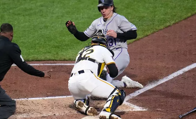 Colorado Rockies' Jake McCarthy, rear, is tagged out by Pittsburgh Pirates catcher Henry Davis attempting to score on a fielder's choice by Brett Sullivan during the fifth inning of a baseball game in Pittsburgh, Wednesday, May 13, 2026. (AP Photo/Gene J. Puskar)