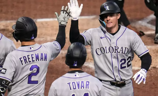 Colorado Rockies' Mickey Moniak (22) is greeted by Tyler Freeman (2) and Ezequiel Tovar (14) as he returns to the dugout after hitting a three-run home run off Pittsburgh Pirates pitcher Mitch Keller during the fifth inning of a baseball game in Pittsburgh, Wednesday, May 13, 2026. (AP Photo/Gene J. Puskar)