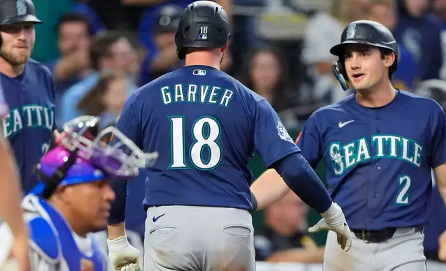Seattle Mariners' Mitch Garver (18) celebrates with Cole Young (2) after hitting a two-run home run during the seventh inning of a baseball game against the Kansas City Royals, Friday, May 22, 2026, in Kansas City, Mo. (AP Photo/Charlie Riedel)
