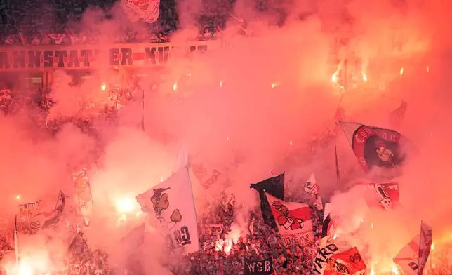 Soccer fans burn flares and hold flags during the DFB Pokal, German Cup final soccer match between VfB Stuttgart and Bayern Munich in Berlin, Germany, Saturday, May 23, 2026. (AP Photo/Ebrahim Noroozi)