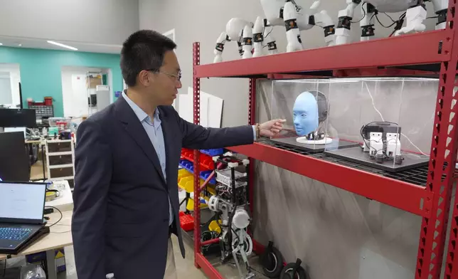 Professor Boyuan Chen gestures toward a humanoid robot at Duke University's General Robotics Lab in Durham, N.C., Tuesday, May 26, 2026. (AP Photo/Allen G. Breed)