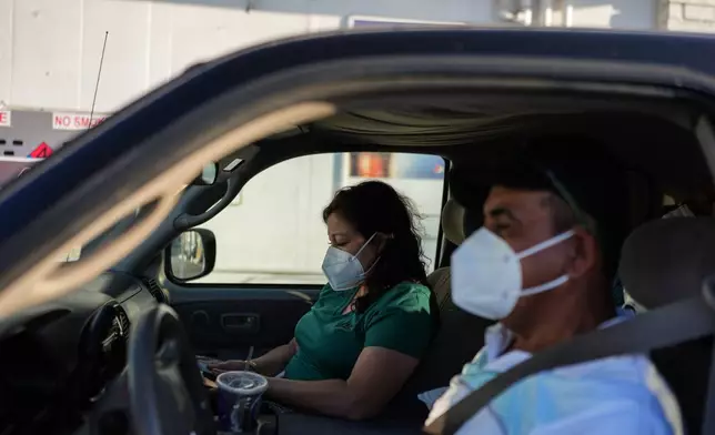 Two evacuees sit in their pickup truck at a gas station within the evacuation zone in Stanton, Calif., Monday, May 25, 2026. (AP Photo/Jae C. Hong)