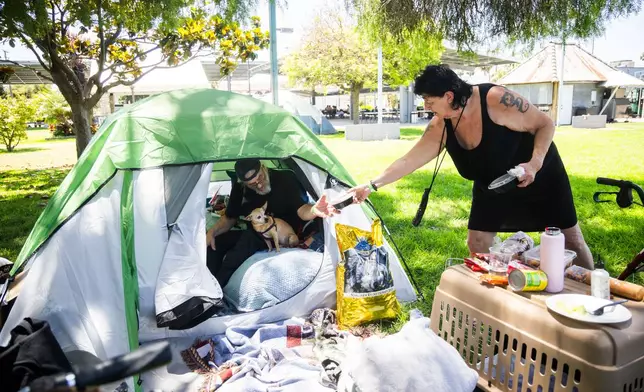 Jan De Jonge and fiancé Sher Stuckman set up a tent with their belonging and pet outside the Elks Lodge in Garden Grove, Calif., on Monday, May 25, 2026. (AP Photo/Ethan Swope)