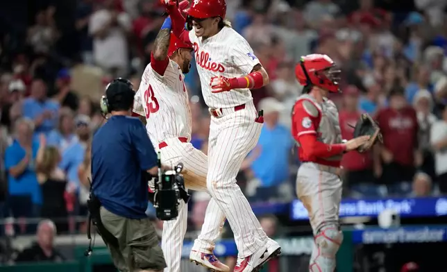 Philadelphia Phillies' Bryson Stott, center, celebrates with Edmundo Sosa, left, after hitting a two-run home run during the eighth inning of a baseball game against the Cincinnati Reds Monday, May 18, 2026, in Philadelphia. (AP Photo/Matt Slocum)