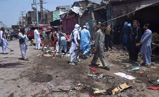 Plainclothes police officers examine damage at the site of a bomb explosion at a market in Sarai Norag in Lakki Marwat, a district in Pakistan's Khyber Pakhtunkhwa province, Tuesday, May 12, 2026. (AP Photo/G.A Marwat)
