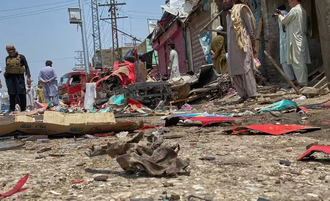 A police officer, left, and local residents examine damage at the site of a bomb explosion at a market in Sarai Norag in Lakki Marwat, a district in Pakistan's Khyber Pakhtunkhwa province, Tuesday, May 12, 2026. (AP Photo/Farhat Ullah)