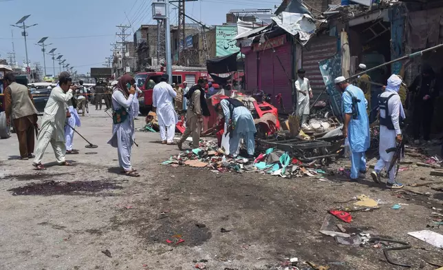 Plainclothes police officers examine damage at the site of a bomb explosion at a market in Sarai Norag in Lakki Marwat, a district in Pakistan's Khyber Pakhtunkhwa province, Tuesday, May 12, 2026. (AP Photo/G.A Marwat)