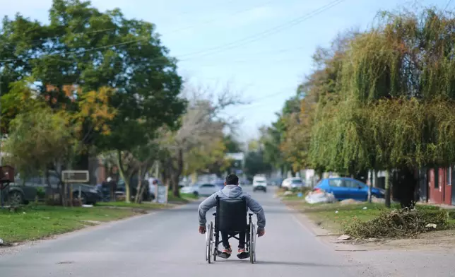 Ivan Ferreiro rides down the street in his wheelchair in Moreno, on the outskirts of Buenos Aires, Argentina Wednesday, May 13, 2026. (AP Photo/Natacha Pisarenko)