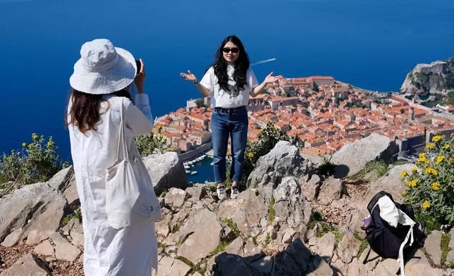 Tourists take photos of themselves on a hill overlooking the old town of Dubrovnik, Croatia, Monday, April 27, 2026. (AP Photo/Darko Bandic)