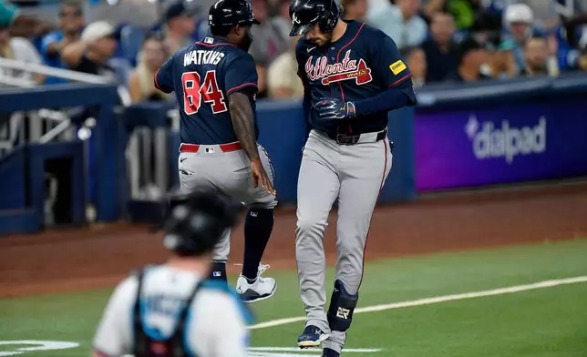Atlanta Braves' Austin Riley, right, celebrates with third base coach Tommy Watkins (84) after hitting a home run during the second inning of a baseball game, Wednesday, May 20, 2026, in Miami. (AP Photo/Michael Laughlin)