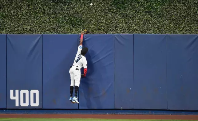 Miami Marlins right fielder Esteury Ruiz (3) reaches for the home run ball hit by Atlanta Braves' Austin Riley during the second inning of a baseball game, Wednesday, May 20, 2026, in Miami. (AP Photo/Michael Laughlin)