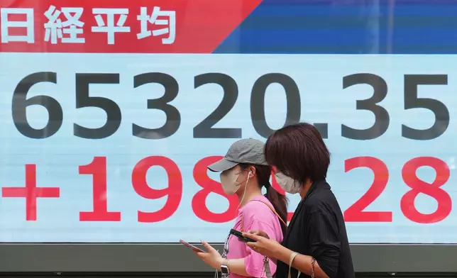 People walk in front of an electronic stock board showing Japan's Nikkei index at a securities firm Monday, May 25, 2026, in Tokyo. (AP Photo/Eugene Hoshiko)