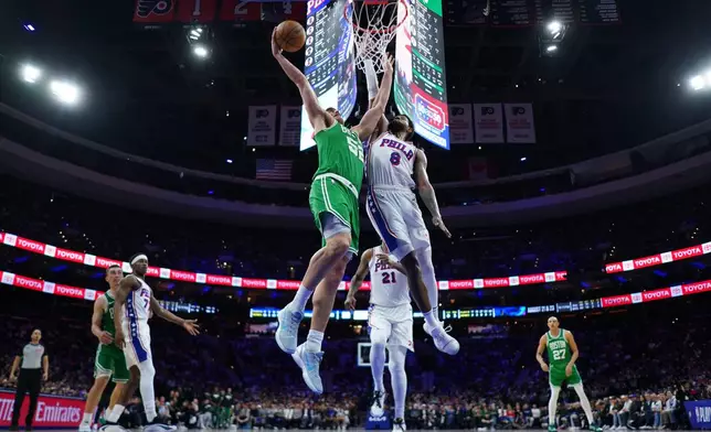 Boston Celtics' Luka Garza, left, goes up for a dunk against Philadelphia 76ers' Paul George during the second half of Game 6 in a first-round NBA basketball playoff series Thursday, April 30, 2026, in Philadelphia. (AP Photo/Matt Slocum)