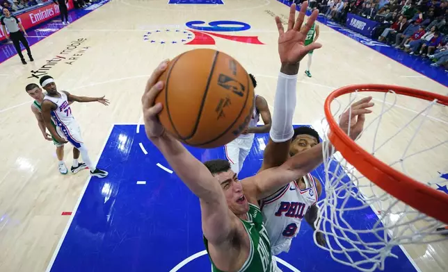 Boston Celtics' Luka Garza, left, goes up for a dunk against Philadelphia 76ers' Paul George during the second half of Game 6 in a first-round NBA basketball playoff series Thursday, April 30, 2026, in Philadelphia. (AP Photo/Matt Slocum)
