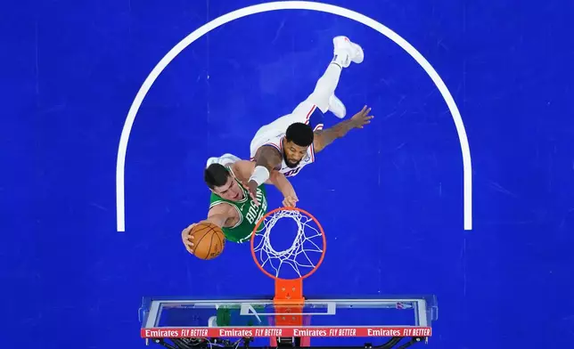 Boston Celtics' Luka Garza, left, goes up for a dunk against Philadelphia 76ers' Paul George during the second half of Game 6 in a first-round NBA basketball playoff series Thursday, April 30, 2026, in Philadelphia. (AP Photo/Matt Slocum)