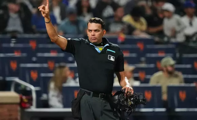 Home plate umpire Emil Jimenez gestures to players during the eighth inning of a baseball game between the New York Mets and the Cincinnati Reds Tuesday, May 26, 2026, in New York. (AP Photo/Frank Franklin II)