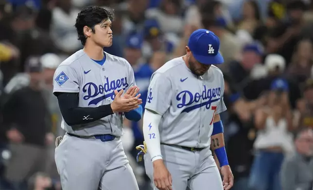 Los Angeles Dodgers starting pitcher Shohei Ohtani, left, celebrates with teammate Miguel Rojas after the Dodgers defeated the San Diego Padres 4-0 in a baseball game Wednesday, May 20, 2026, in San Diego. (AP Photo/Gregory Bull)