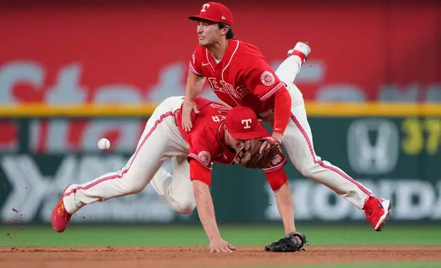 Texas Rangers shortstop Corey Seager, left, and second baseman Justin Foscue collide while fielding a ball hit by Chicago Cubs' Nico Hoerner during the seventh inning of a baseball game Friday, May 8, 2026, in Arlington, Texas. (AP Photo/Julio Cortez)