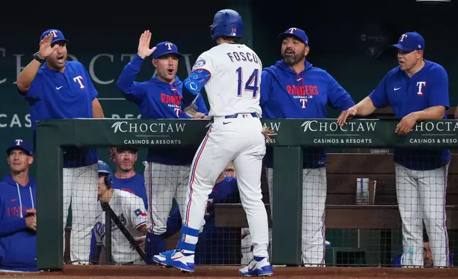 Texas Rangers' Justin Foscue (14) reacts with manager Skip Schumaker, second from left, and staff after hitting his first career home run during the third inning of a baseball game against the Chicago Cubs Saturday, May 9, 2026, in Arlington, Texas. (AP Photo/Julio Cortez)
