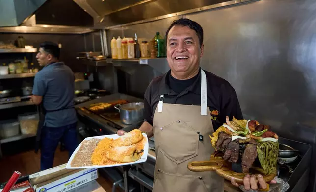 Mexican restaurant owner-chef Marco Mendoza prepares a hot molcajete, a traditional Mexican dish, at Cuernavaca's Grill in downtown Los Angeles, Tuesday, April 28, 2026. (AP Photo/Damian Dovarganes)