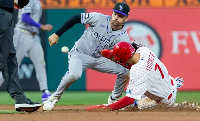 Philadelphia Phillies' Trea Turner (7) slides into second as Colorado Rockies second baseman Edouard Julien, second from right, waits for the ball to tag him out in the fourth inning of a baseball game, Saturday, May 9, 2026, in Philadelphia. (AP Photo/Laurence Kesterson)