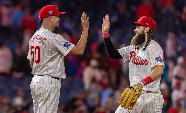 Philadelphia Phillies closing pitcher Orion Kerkering (50) is congratulated by left fielder Brandon Marsh after their team defeated the Colorado Rockies in a baseball game, Saturday, May 9, 2026, in Philadelphia. (AP Photo/Laurence Kesterson)