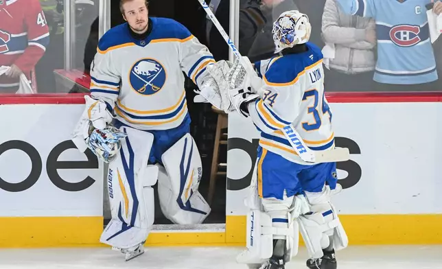 Buffalo Sabres goaltender Alex Lyon (34) touches gloves with fellow goalie Ukko-Pekka Luukkonen, left, after being pulled during the first period of Game 6 in a second-round NHL hockey Stanley Cup playoff series against the Montreal Canadiens in Montreal, Saturday, May 16, 2026. (Graham Hughes/The Canadian Press via AP)
