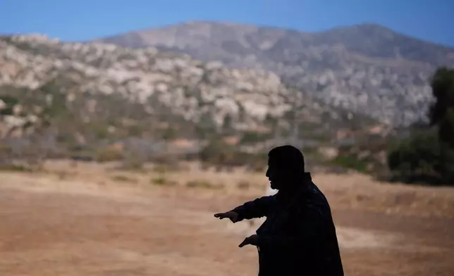Norma Meza Calles, a Kumeyaay Nation leader, gestures as she speaks of the sacred importance of Kuuchamaa Mountain, behind, at a wellness center, Friday, May 1, 2026, in Tecate, Mexico. (AP Photo/Gregory Bull)
