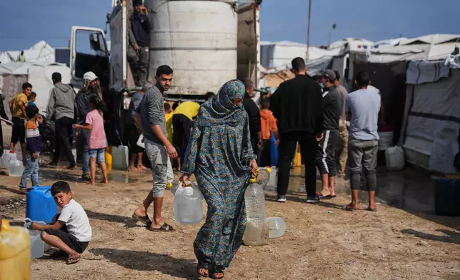 Samah Abu Daqqa, 33, carries jerrycans filled with water through a tent camp in Khan Younis, in the southern Gaza Strip, Thursday, April 30, 2026. (AP Photo/Abdel Kareem Hana)