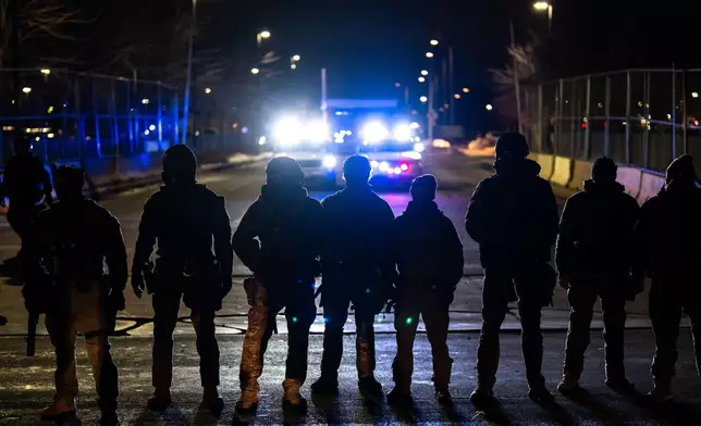 FILE - Federal officers stand guard after detaining people outside of Bishop Henry Whipple Federal Building, Jan. 13, 2026, in Minneapolis. (AP Photo/Adam Gray, File)