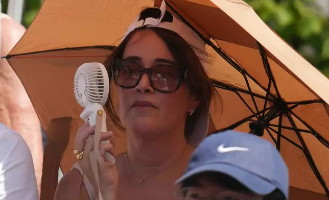 A woman cools herself with a portable fan during the first round men's singles tennis match between Alex De Minaur of Australia and Toby Samuel of Britain at the French Open tennis tournament in Paris, Monday, May 25, 2026. (AP Photo/Christophe Ena)