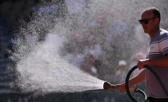 A stadium worker sprays the court with water before the first round men's singles tennis match at the French Open tennis tournament in Paris, Monday, May 25, 2026. (AP Photo/Aurelien Morissard)