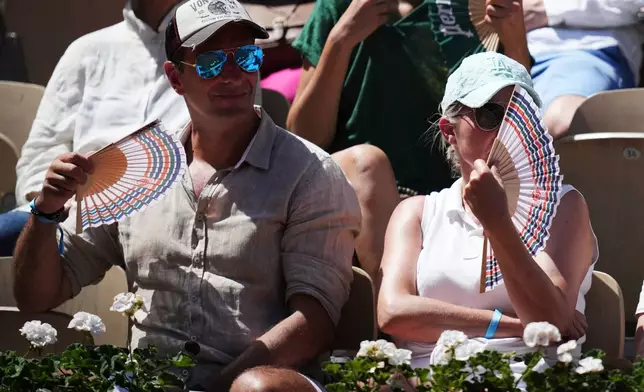 Spectators cool themselves with hand fans during the first round women's singles tennis match between Elina Svitolina of Ukraine and Anna Bondar of Hungary at the French Open tennis tournament in Paris, Monday, May 25, 2026. (AP Photo/Christophe Ena)