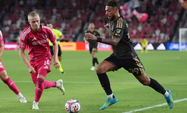 Los Angeles FC's Denis Bouanga (99) and St. Louis City's Tomas Totland (14) battle for the ball during the first half of an MLS soccer match Wednesday, May 13, 2026, in St. Louis. (AP Photo/Jeff Roberson)