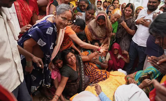 Relatives mourn beside the body of Summit Yadav, 24, who died after the wall of his neighbor's house collapsed following dust storms and heavy rain in Prayagraj, India, Thursday, May 14, 2026. (AP Photo/Rajesh Kumar Singh) CORRECTION: Corrected to that Yadav died after the wall of his neighbor's house collapsed, not his own house's.