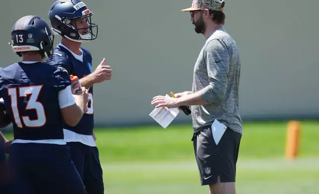 Denver Broncos offensive coordinator Davis Webb, right, confers with quarterbacks E.J. Warner (13) and Nathan Peterman, second from left, during drills at the NFL football team's rookie minicamp Saturday, May 9, 2026, at the team's headquarters in Centennial, Colo. (AP Photo/David Zalubowski)