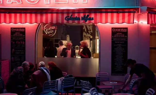 Festivalgoers eat at an ice cream shop near the 79th international film festival, Cannes, southern France, Sunday, May 17, 2026. (AP Photo/John Locher)