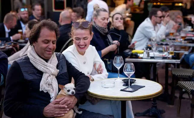 A man holds a dog in a bar during the 79th international film festival, Cannes, southern France, Tuesday, May 19, 2026. (AP Photo/Andreea Alexandru)
