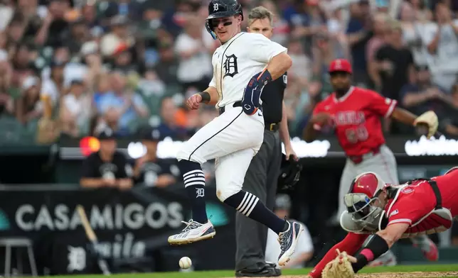 Detroit Tigers' Kevin McGonigle, left, avoids the ball while scoring as Los Angeles Angels catcher Logan O'Hoppe (14) attempts to stop the throw during the fifth inning of a baseball game Wednesday, May 27, 2026, in Detroit. (AP Photo/Paul Sancya)