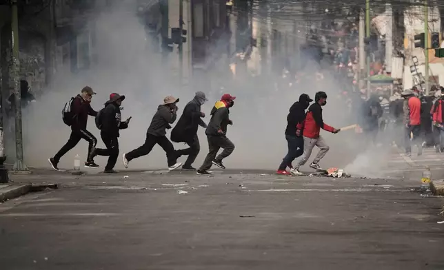 Demonstrators run across a street during an anti-government protest in La Paz, Bolivia, Monday, May 18, 2026. (AP Photo/Freddy Barragan)