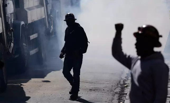 Miners stand amid smoke from tear gas and firecrackers during clashes with police at an anti-government protest in La Paz, Bolivia, Monday, May 18, 2026. (AP Photo/Juan Karita)