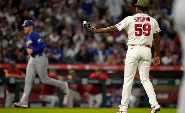 Los Angeles Angels pitcher José Soriano, right, stands by as Los Angeles Dodgers' Freddie Freeman heads home on a walk by Max Muncy during the sixth inning of a baseball game Saturday, May 16, 2026, in Anaheim, Calif. (AP Photo/Mark J. Terrill)