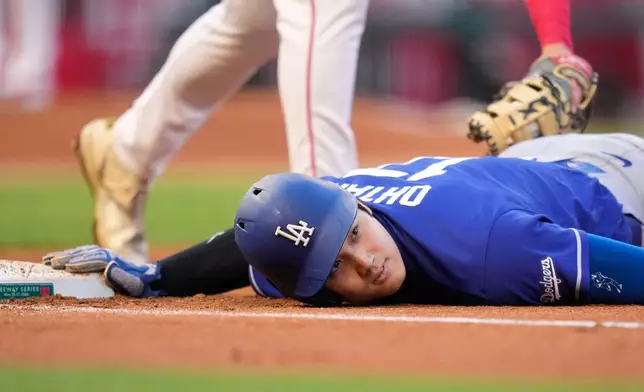 Los Angeles Dodgers' Shohei Ohtani, below, dives back to first under the tag of Los Angeles Angels first baseman Nolan Schanuel during the third inning of a baseball game Saturday, May 16, 2026, in Anaheim, Calif. (AP Photo/Mark J. Terrill)
