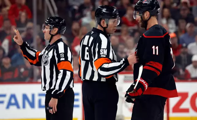 Referee Gord Dwyer (19) announces a call while referee Francis Charron (6) espeaks to Carolina Hurricanes' Jordan Staal (11) during the third period of Game 2 of an NHL hockey Stanley Cup second-round playoff series against the Philadelphia Flyers in Raleigh, N.C., Monday, May 4, 2026. (AP Photo/Karl DeBlaker)