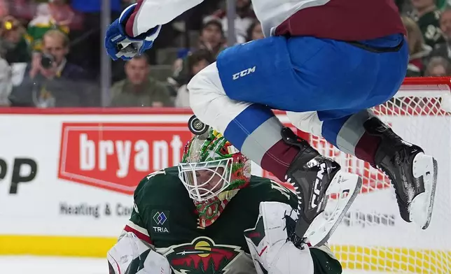 Minnesota Wild goaltender Jesper Wallstedt, bottom, defends against a shot while pressured by Colorado Avalanche center Nathan MacKinnon (29) during the second period of Game 3 of an NHL Stanley Cup hockey second-round playoff series, Saturday, May 9, 2026, in St. Paul, Minn. (AP Photo/Abbie Parr)