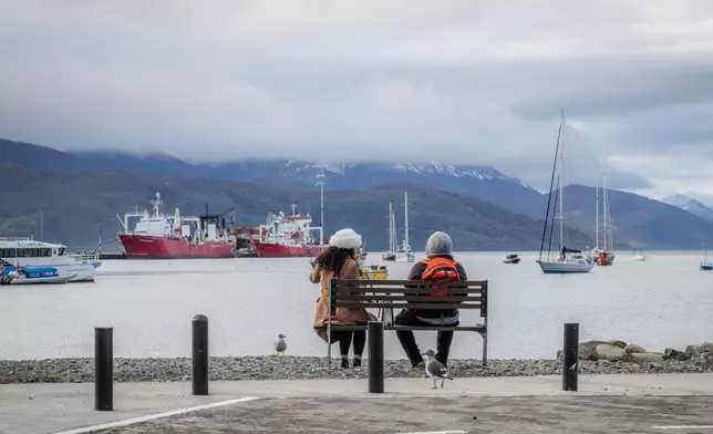 People sit on a bench in Ushuaia, Argentina, Thursday, May 14, 2026. (AP Photo/Joel Reyero)