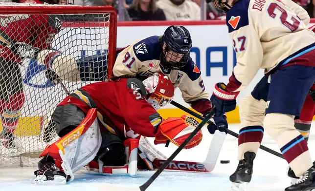 Montreal Victoire's Maggie Flaherty (91) leans over Ottawa Charge goaltender Gwyneth Philips, center bottom, as she looks for the puck at the net during the first period of Game 3 in the PWHL Walter Cup finals hockey series in Ottawa, Ontario, Monday May 18, 2026. (Justin Tang/The Canadian Press via AP)